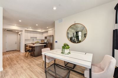 dining area with table and chairs. Round wall mirror on dining room wall and kitchen island in the background.